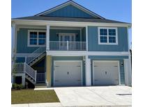 Inviting two-story home features light blue siding, white trim, double garage, and a charming second-story balcony at 2307 Tortuga Ln., North Myrtle Beach, SC 29582