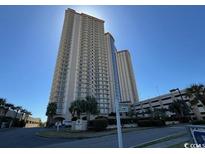 High-rise condo building with balconies and manicured landscaping under a clear blue sky at 8500 Margate Circle # 2005, Myrtle Beach, SC 29572