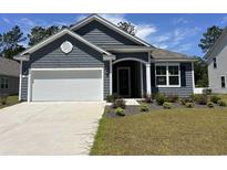 Charming home featuring a two-car garage, beautiful landscaping, and classic architectural details, all set under a sunny sky at 124 Fair Meadow Ct., Loris, SC 29569