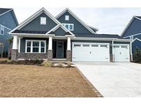 Two-story home with gray siding, brick accents, and a three-car garage at 2369 Vera Way, Longs, SC 29568