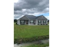 Charming single-story home featuring gray siding, a dark metal roof and well-manicured lawn on a cloudy day at Tbd 17 Privetts Rd., Conway, SC 29526