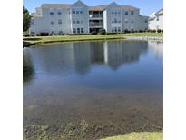 Condos with a pond view, lush green grass, and manicured shrubs on a sunny day at 2276 Essex Dr. # A, Myrtle Beach, SC 29575