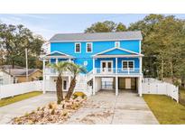 Bright blue coastal style home with dual staircases and landscaping of palm trees and decorative white stone at 514 Vista Dr., Murrells Inlet, SC 29576