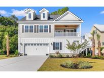 Charming two-story home featuring a covered porch, dormer windows, and a two-car garage with beautiful landscaping at 132 Oak Bay Dr., Georgetown, SC 29440