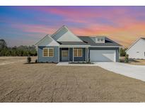 New construction home features blue siding, white trim, and a two-car garage at 381 Log Cabin Rd., Loris, SC 29569