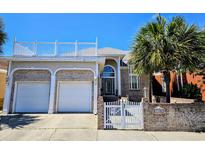 Beautiful two-story brick home with a white fence and a well-manicured lawn and roof top deck at 144 Waterway Crossing Ct., Little River, SC 29566