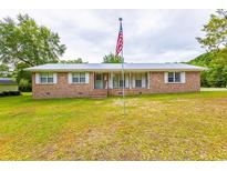 Charming single-story brick home featuring a metal roof and a spacious front yard with mature trees at 705 White Oak Dr., Johnsonville, SC 29555