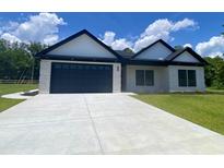 Charming home featuring a black garage door, white brick, dark roof and a concrete driveway at 205 Brush Ct., Little River, SC 29566