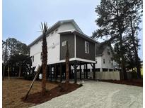 Charming beach house on stilts, featuring durable siding and a gravel driveway at 189 Brown Pelican Loop, Pawleys Island, SC 29585