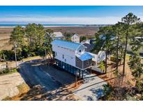 An inviting two-story home with a metal roof is situated on a stilt foundation near the ocean at 189 Brown Pelican Loop, Pawleys Island, SC 29585