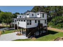 Stunning modern home featuring elevated design, stylish white siding, and eye-catching dark trim at 216 Brown Pelican Loop, Pawleys Island, SC 29585