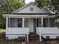 Charming single-story home with a covered front porch, white siding, and brick stairs, ready for renovation at 114 Henry Mcgill St., Marion, SC 29571