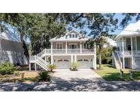 Charming raised beach home with a white exterior, a balcony, a two-car garage, and a well-manicured front yard at 590 Collins Ave., Murrells Inlet, SC 29576