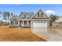 Charming gray brick home featuring a two-car garage, dormer windows, and manicured front lawn at 2264 Pearl Rd., Galivants Ferry, SC 29544