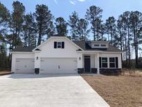 Charming single-story home featuring white siding, a two-car garage, and a well-manicured front yard at 1587 Highway 701 South, Loris, SC 29569
