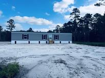 New manufactured home with gray siding, black shutters, and a sandy front yard under a blue sky at 2494 Newton Rd., Aynor, SC 29511