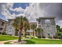 Attractive condo building showcasing a neatly manicured lawn, palm trees, and elegant stone and stucco exterior at 4709 Wild Iris Dr. # 104, Myrtle Beach, SC 29577