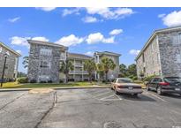 Condo complex featuring a stone and stucco exterior with palm trees and well-maintained landscaping at 4709 Wild Iris Dr. # 104, Myrtle Beach, SC 29577
