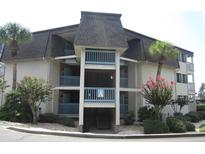 Two-story condo building with light-colored siding, balconies, and landscaping at 5601 Ocean Blvd. N # 202 A, Myrtle Beach, SC 29577