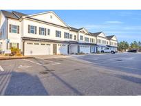 Row of new townhomes with white siding, black shutters, and individual garages in a large parking lot at Lot 40 Lineback Pl. # 40, Longs, SC 29568