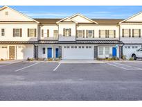 New townhomes with white siding, black shutters, blue doors, and two-car garages in a community with ample parking at Lot 41 Lineback Pl. # 41, Longs, SC 29568