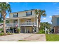 Charming two-story home with double decks, car port, mature palms, and a paved drive under a bright blue sky at 213 South Myrtle Dr., Surfside Beach, SC 29575