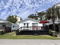 Charming white cottage with black deck and a bright red umbrella for a vibrant, inviting look at 6001 - 5410 S Kings Hwy., Myrtle Beach, SC 29575