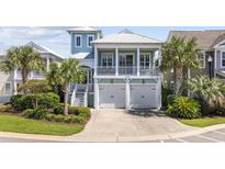 Charming two-story home featuring a light-green exterior, a white metal roof, and a two-car garage at 4989 Salt Creek Ct., North Myrtle Beach, SC 29582