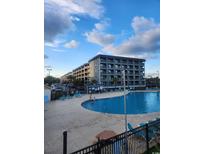 Resort exterior featuring an outdoor swimming pool and manicured grounds under a partly cloudy sky at 5905 S Kings Highway # 405 A, Myrtle Beach, SC 29575