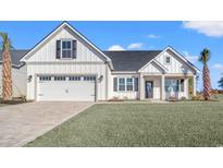 White farmhouse exterior with a two-car garage and a nicely landscaped lawn at 1409 Crooked Hook Rd., North Myrtle Beach, SC 29582