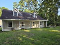 Charming home with a quaint front porch and dormer windows, surrounded by lush greenery at 938 Fox Hollow Rd., Conway, SC 29526