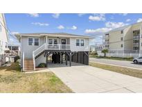 Charming home with a light gray exterior, elevated design, and a convenient drive-under parking area at 300 46Th Ave. N, North Myrtle Beach, SC 29582