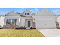 White house with gray shutters, brick accents, and a two-car garage at 371 Lifestyle Court, Surfside Beach, SC 29575