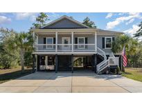 Inviting two-story home featuring gray siding, white columns and railings, and a spacious carport at 100 Lure Ct., Conway, SC 29526