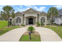 Stunning stucco home featuring a circular driveway, arched windows, and tropical landscaping at 202 Ave. Of The Palms, Myrtle Beach, SC 29579