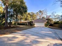 Charming brick home with a large driveway and well-maintained landscaping beneath a canopy of mature trees at 902 N 11Th Ave. N, North Myrtle Beach, SC 29582
