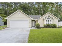 Charming single-story home featuring a two-car garage, manicured lawn, and mature trees at 251 Galapagos Dr., Little River, SC 29566