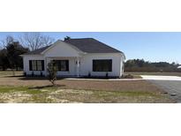 Charming white home with well-manicured front yard, black framed windows, and a modern exterior design at 107 Deans Ct., Green Sea, SC 29545