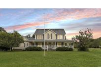 Inviting two-story home with a large front yard and charming wrap-around porch, perfect for relaxing evenings at 9396 S Highway 905, Longs, SC 29568