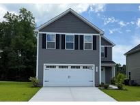 Two-story home featuring a two-car garage, black shutters, gray siding, and manicured landscaping at 1055 Oak Meadow Dr., Conway, SC 29526