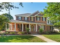 Stately brick home featuring a covered front porch with columns and manicured landscaping in a lush lawn at 9325 Cove Dr., Myrtle Beach, SC 29572