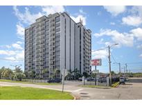 Tall condominium building Holiday Towers with manicured green lawn and parking at 601 Mitchell Dr. # 401, Myrtle Beach, SC 29577