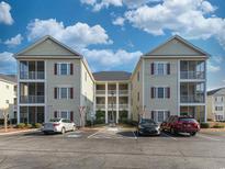 Condominium complex featuring multiple units, screened porches and ample parking under a partly cloudy sky at 2060 Cross Gate Blvd. # 305, Surfside Beach, SC 29575