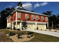 Two-story home with orange siding, multiple garages, and landscaping at 110 Hallandale Lane, Murrells Inlet, SC 29576