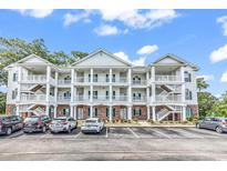 Three-story condo building with white siding, balconies, and well-maintained landscaping at 4459 Turtle Ln. # 1C, Little River, SC 29566