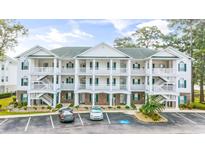 Three-story condo building featuring balconies, white railings, brick accents, and convenient parking spaces at 4430 Turtle Ln. # 2-C, Little River, SC 29566