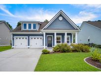 Charming blue two-story home with a well-manicured lawn, two-car garage, and inviting front porch at 306 Southgate Ct., Pawleys Island, SC 29585