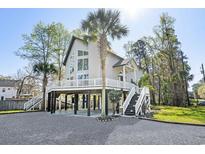 Coastal home featuring a lifted structure, large windows, and dual staircases leading to a wraparound porch at 5800 Creekside Dr., Myrtle Beach, SC 29588