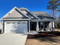 Gray house with white trim, two-car garage, and landscaped yard at 908 Anemone Ct Nw, Calabash, NC 28467