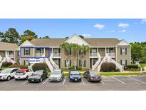 Exterior view of a two-story condo building with palm trees, white stairs and parking at 1137 Peace Pipe Ln. # 201, Myrtle Beach, SC 29579